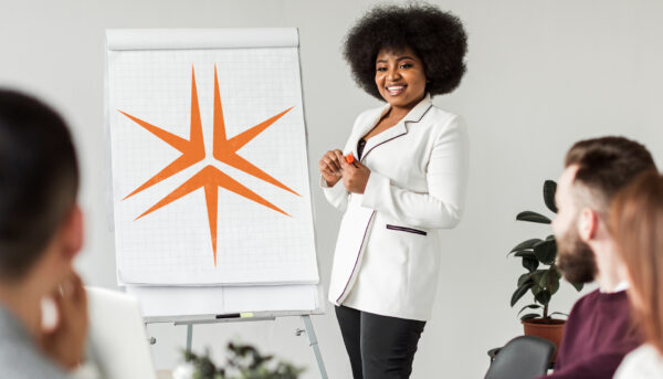 Young professional women stands in front of an easel and flipchart giving a presentation to her colleagues