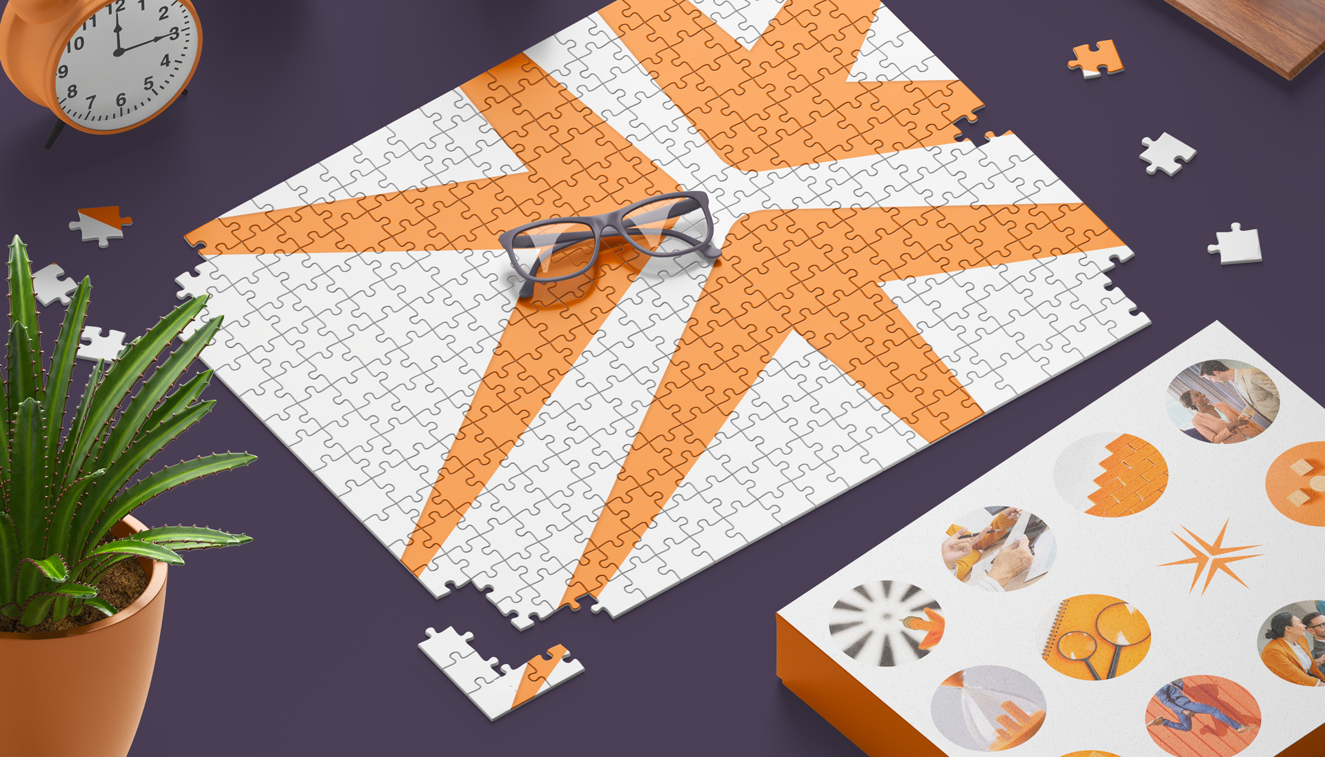 A pair of glasses on a partially completed jigsaw puzzle. There is a plant in one corner and the puzzle box in the other. The pattern of the puzzle is the Miller Thomson spark.