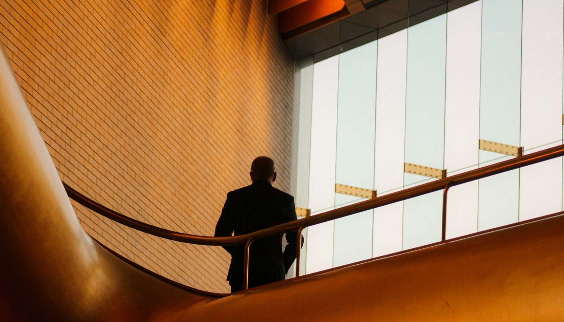 Silhouette of a man standing next to railing on upper floor of a building