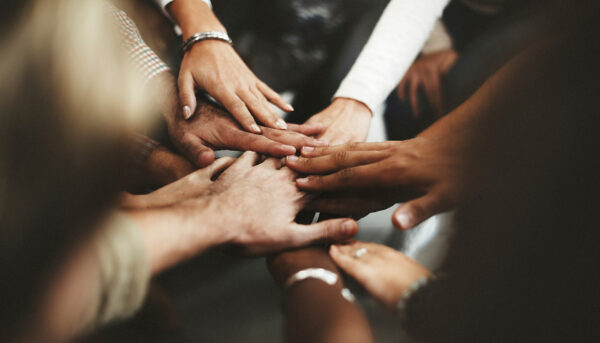 group of people extending their hands into the centre of a circle