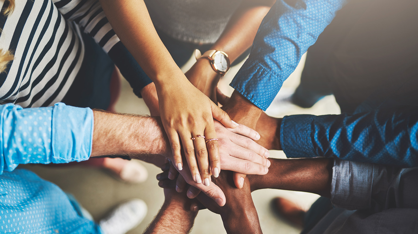 people standing in a circle with hands extended towards the middle