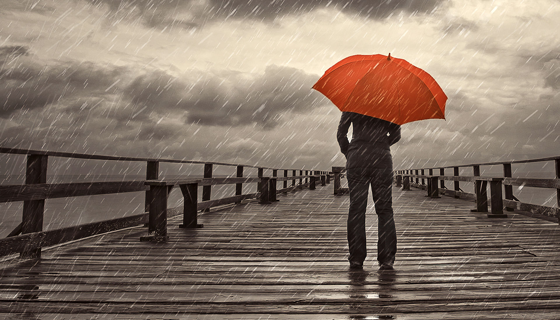 man in a suit standing on a pier holding an umbrella