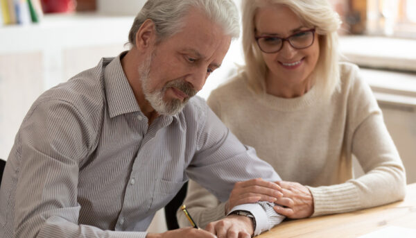 Older couple sitting at table, signing documents