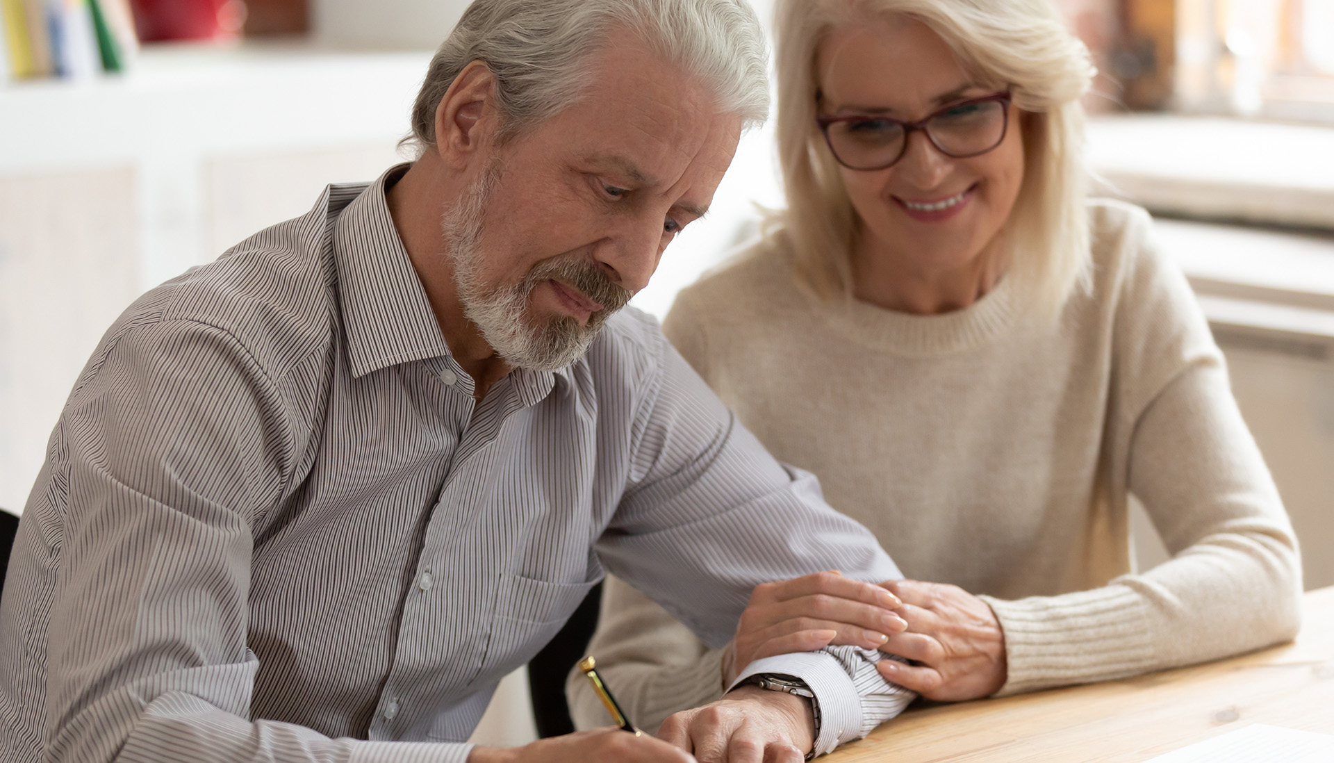 Older couple sitting at table, signing documents