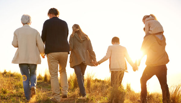 family of three generations walking in park at autumn