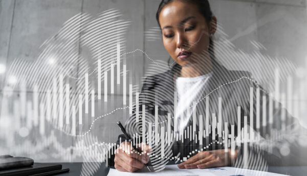 young asian woman signing documents with an overlay of financial graphs depicting stock market analysis