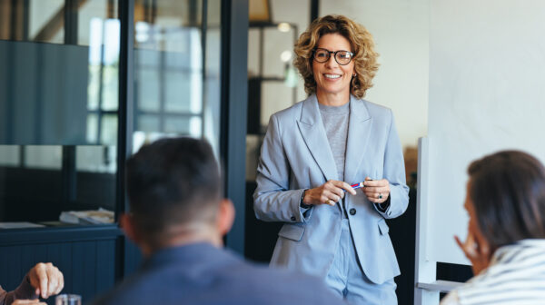woman standing in a conference room giving a presentation to a group of people