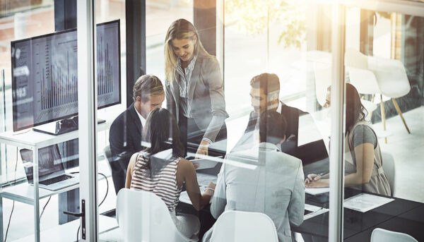 a group of work colleagues in a meeting room with a graph on a tv screen