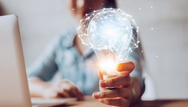 woman working on laptop holding a lightbulb
