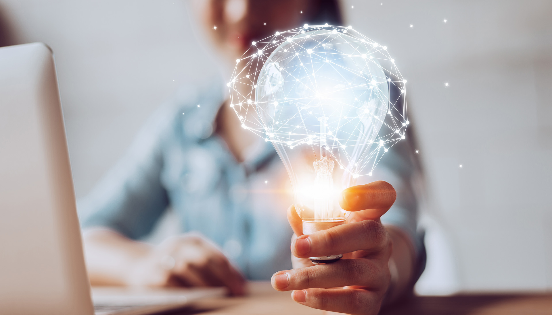 woman working on laptop holding a lightbulb