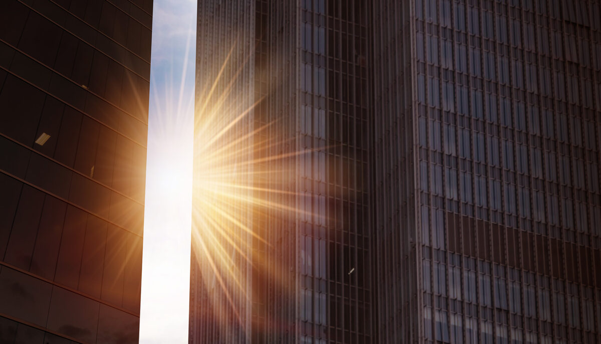 sun rising between two office towers