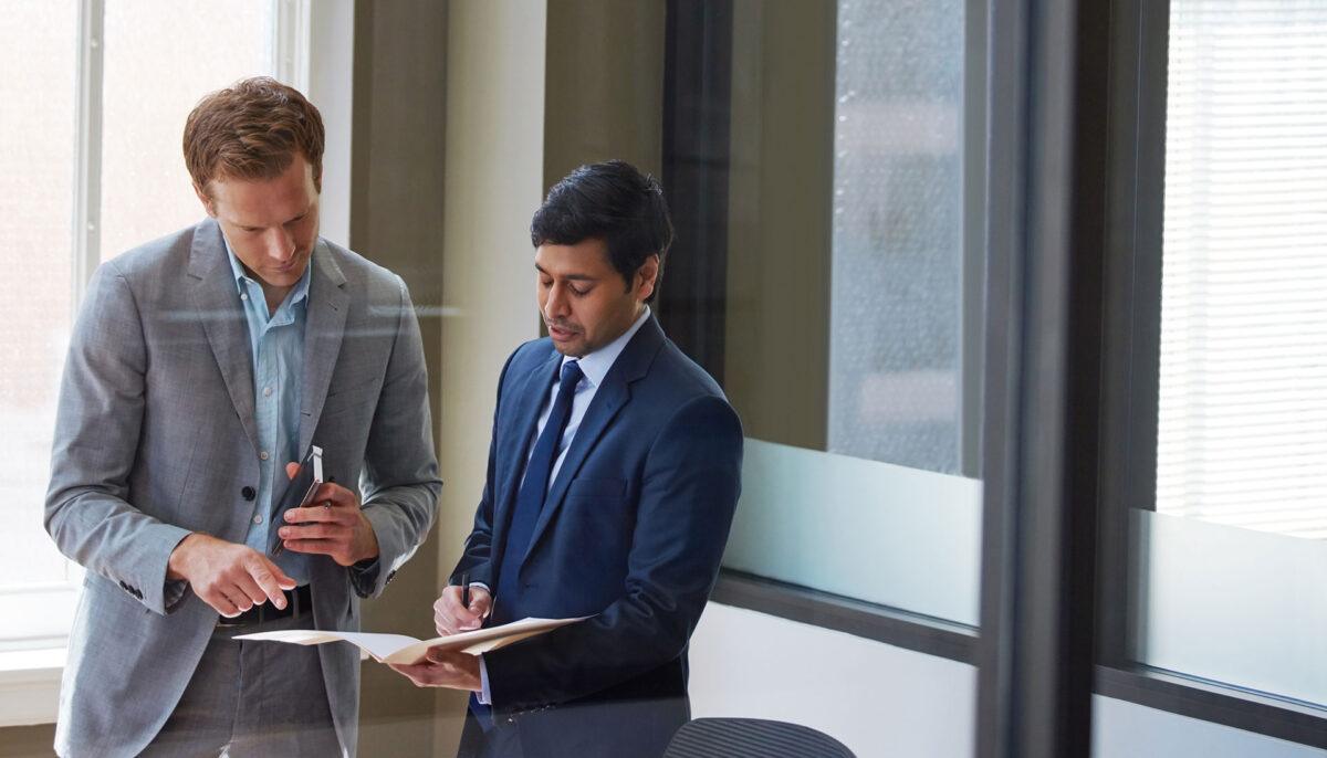 two male colleagues looking over documents in a boardroom