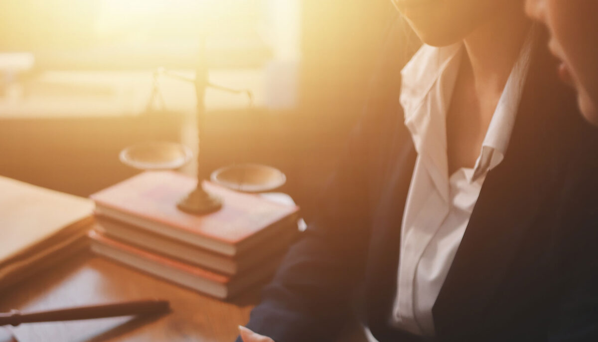 Female lawyer with scales of justice on a stack of books in the background