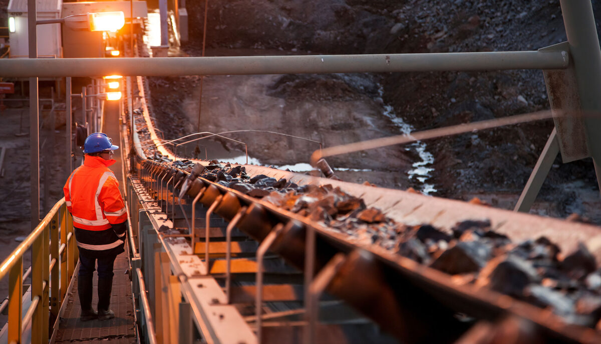 Mine worker inspecting a conveyor belt carrying ore