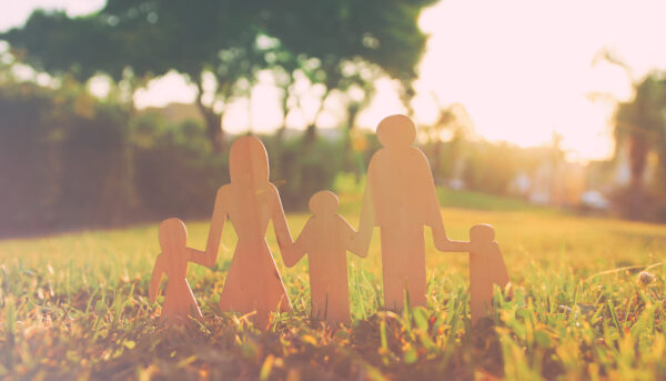 paper cutouts depicting multi-generational family  placed in a field with trees in the far background