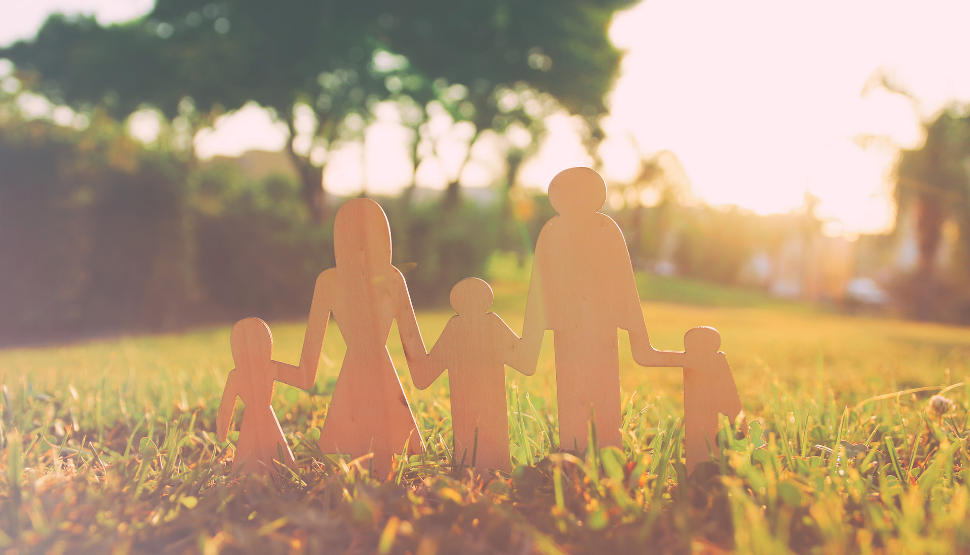 paper cutouts depicting multi-generational family placed in a field with trees in the far background