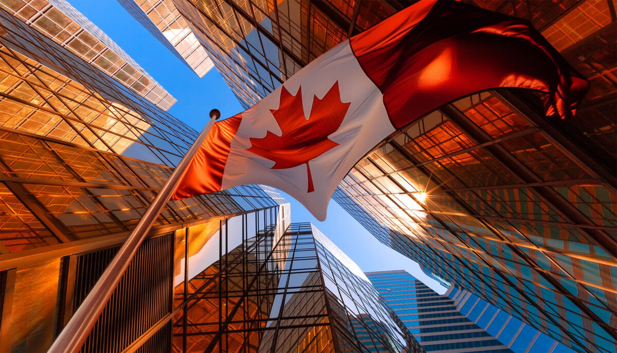 Looking up at the Canadian flag with high rise office towers in the background